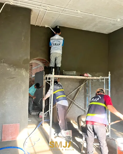 Công nhân thi công lắp đặt hệ thống ống điện đi nổi trên trần bê tông và trát tường hoàn thiện tại công trình nhà phố.