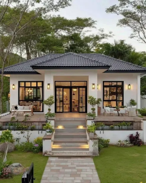 Nhà cấp 4 mái Nhật mặt tiền trắng, hệ cửa kính chia ô màu đen, bậc tam cấp cao gắn đèn led và sân vườn xanh mát.