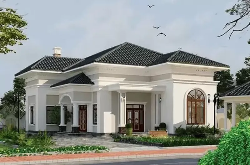Biệt thự vườn cấp 4 mái Nhật tân cổ điển màu trắng kem, thiết kế cửa sổ vòm gỗ kính lớn, cửa chính bằng gỗ đen và khoảng sân vườn rộng rãi.