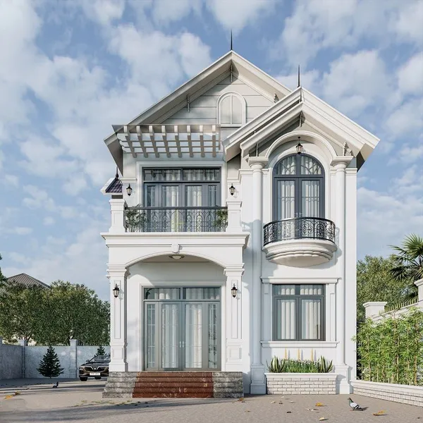 Mẫu biệt thự tân cổ điển 2 tầng mái Thái màu trắng phối xám nhạt, mặt tiền hai gian sang trọng có ban công sắt nghệ thuật, ô cửa sổ mái vòm và giàn lam bê tông trang nhã.