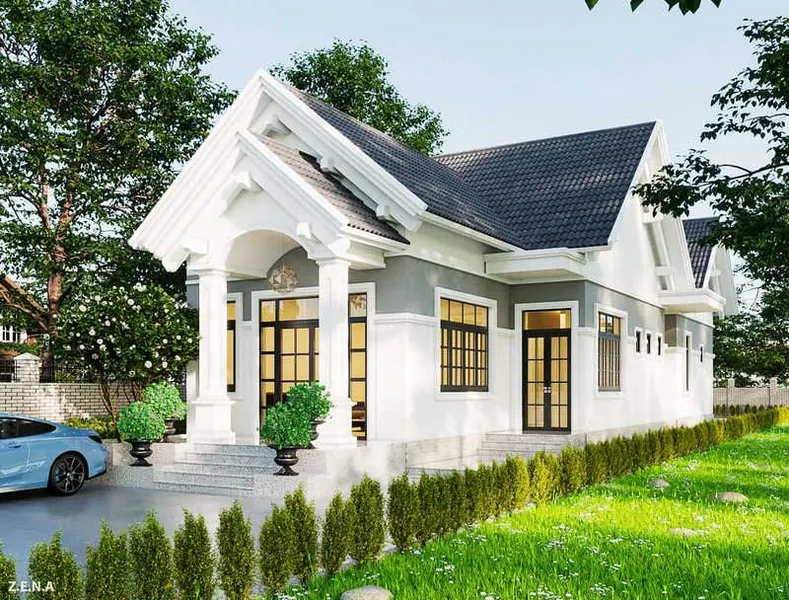 Mẫu nhà cấp 4 mái Thái hiện đại màu trắng phối ghi xám, mặt tiền có sảnh đón vòm cong, hệ cột tròn vững chãi và sân vườn tràn ngập sắc xanh.