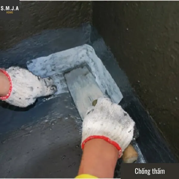 Thợ xây đang thi công dán lưới và quét chất chống thấm chuyên dụng tại góc chân tường công trình nhà ống.
