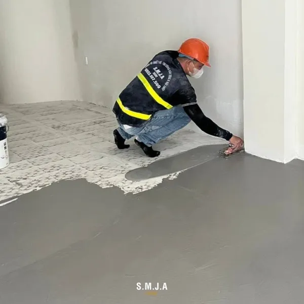 Thợ xây đang thi công quét lớp chống thấm chuyên dụng lên bề mặt sàn bê tông trong công trình nhà ống.